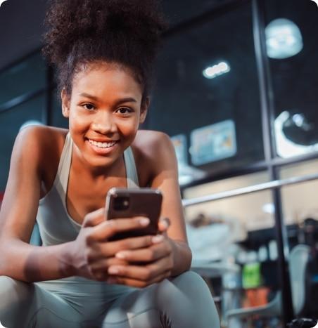 Young woman in fitness clothing checks phone.